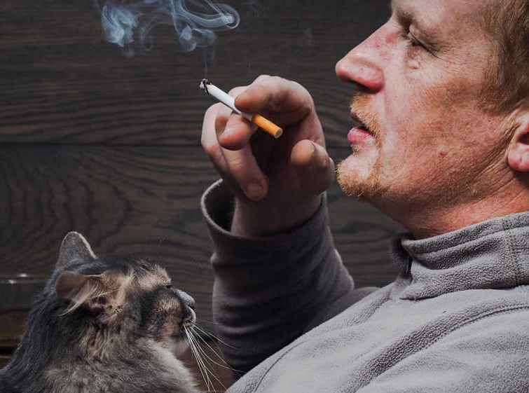 Man smoking with cat on lap