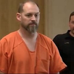 Smirking Stanford. It looks like he was joking with the police officer or court official behind him before he entered court. A disdain for the proceedings and the rule of law.