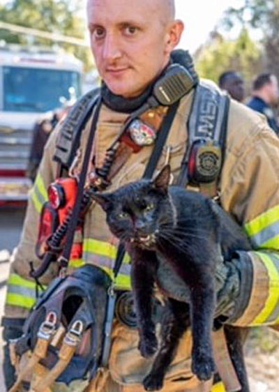 Picture of quizzical firefigher and agitated black cat